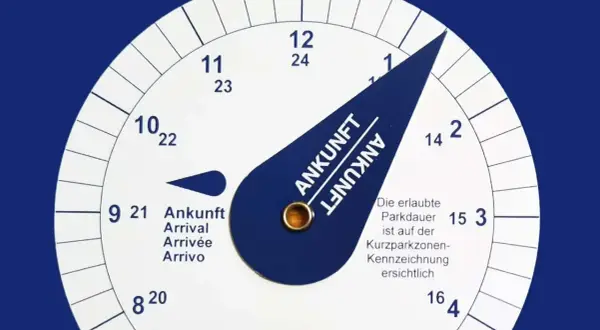 Eine Parkscheibe zeigt die Ankunftszeit. Man muss die Parkscheibe aufrunden, um die erlaubte Parkdauer einzuhalten.