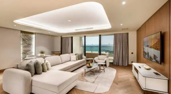 Luxuriöses Wohnzimmer mit Meerblick im Regnum The Crown Belek. Ein großes Ecksofa lädt zum Entspannen ein.