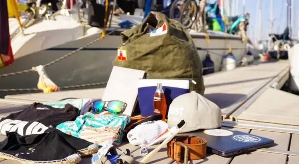 Packliste Segeln: Kleidung, Sonnenbrille, Zahnbürste, Gürtel, Laptop und eine Tasche. Bereit für das Abenteuer auf dem Wasser!
