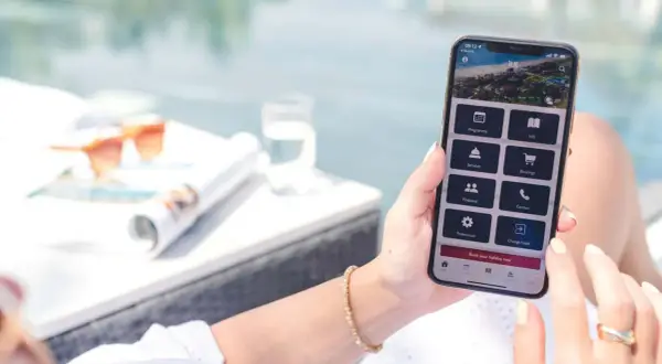 Frau nutzt Handy-App, um eine TUI Reise zu stornieren. Auf dem Bildschirm sind Optionen wie "Bookings" und "Change hotel" sichtbar.