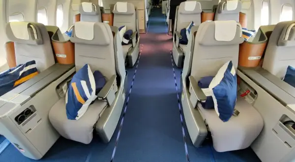 Lufthansa Business Class Sitze mit blauen Kissen und Decken. Ein Blick in den Gang, der Hoffnung auf einen Standby-Ticket-Lufthansa-Traumflug macht.