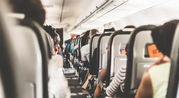 Blick in die enge Flugzeugkabine, wo die Sitze dicht an dicht stehen. Ein Gefühl von Platzangst im Flugzeug kann aufkommen, wenn man die vielen Passagiere sieht.