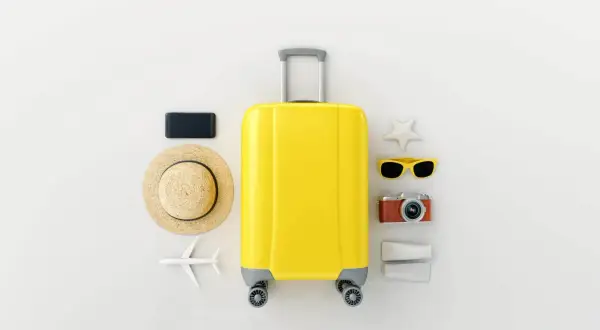 Gelbe Reisetasche mit Hut, Sonnenbrille, Kamera, Handy und Flugzeug – die perfekten roadtrip must haves für deinen Urlaub.