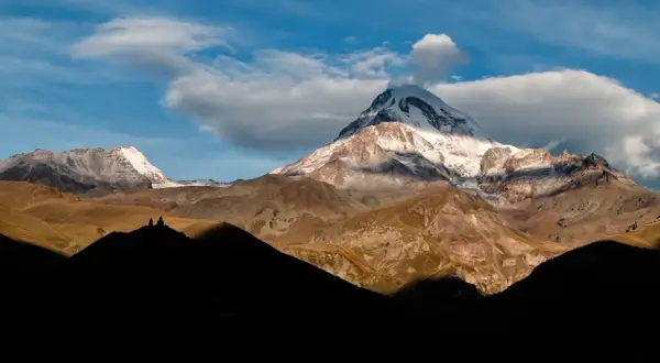 Majestätische Berge in Georgien, ein unvergesslicher Urlaub. Die Gergeti-Dreifaltigkeitskirche thront auf einem Hügel vor dem schneebedeckten Gipfel des Kasbek.