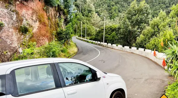 Ein weißer Mietwagen auf einer kurvigen Straße auf Madeira. Braucht man auf Madeira einen Mietwagen? Ja, um diese Aussicht zu genießen!