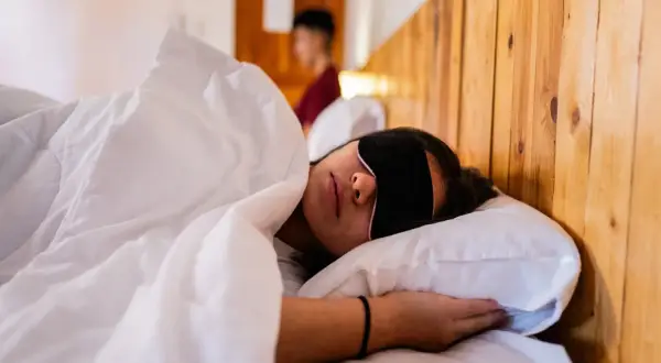 Frau schläft mit Schlafmaske, um Jetlag zu bekämpfen. Die Richtung des Jetlags ist egal, Hauptsache Schlaf.