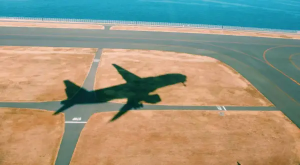 Schatten eines Flugzeugs auf dem Rollfeld. Gute tipps langstreckenflug: entspannt bleiben, Wasser trinken, bewegen.