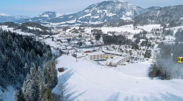 Winteridylle am Robinson Fieberbrunn: Hotelanlage mit Skilift und verschneiten Bergen im Hintergrund.