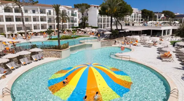 Bunte Wasserrutsche im Pool des Viva Cala Mesquida Resort & Spa. Kinder planschen im Wasser.