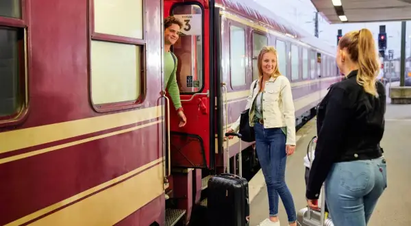 Junge Leute mit Gepäck steigen in den Zug für ihre TUI Bahnreise.