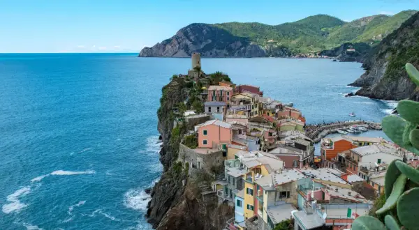 Bunte Häuser kleben an steilen Klippen am Meer. Ein perfekter Urlaub in Italien, mit Blick auf das azurblaue Meer und die Berge.