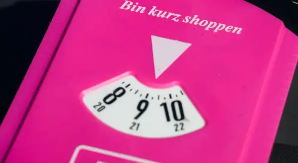 Pink parkschein mit der Aufschrift "Bin kurz shoppen". Die Parkscheibe ist auf 9 Uhr eingestellt.