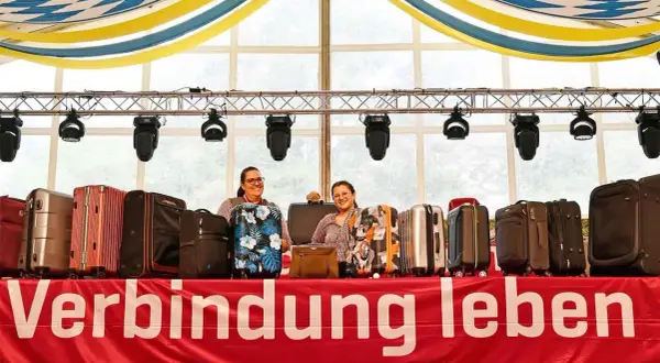 Zwei Frauen präsentieren eine Auswahl an Koffern für eine Auktion. Die Koffer sind in verschiedenen Farben und Mustern erhältlich.