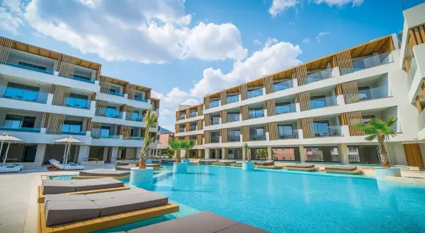 Entspannter Urlaub im Akasha Beach Hotel & Spa: Moderne Architektur, ein einladender Pool und Liegen unter blauem Himmel.