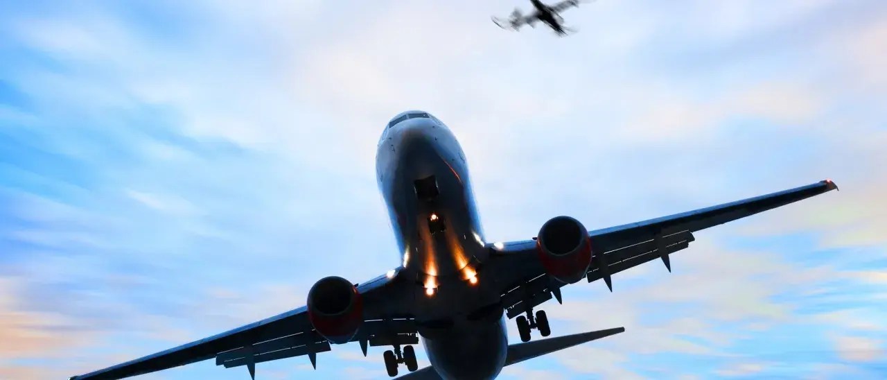 Ein landendes Flugzeug mit ausgefahrenem Fahrwerk im Gegenlicht, ein weiteres Flugzeug fliegt darüber.