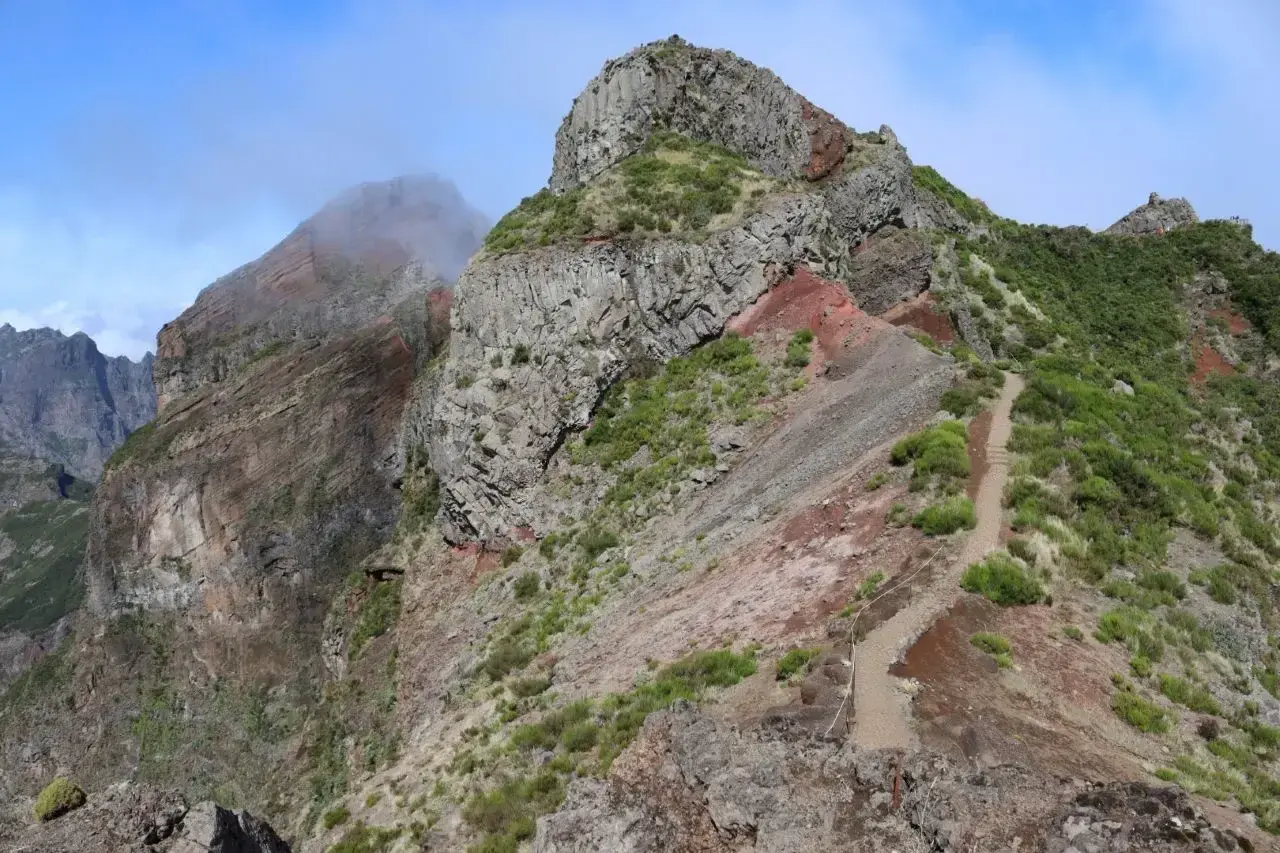 Steiler Wanderweg auf Madeira, ideal für die Packliste. Felsen und grüne Vegetation prägen die Landschaft.