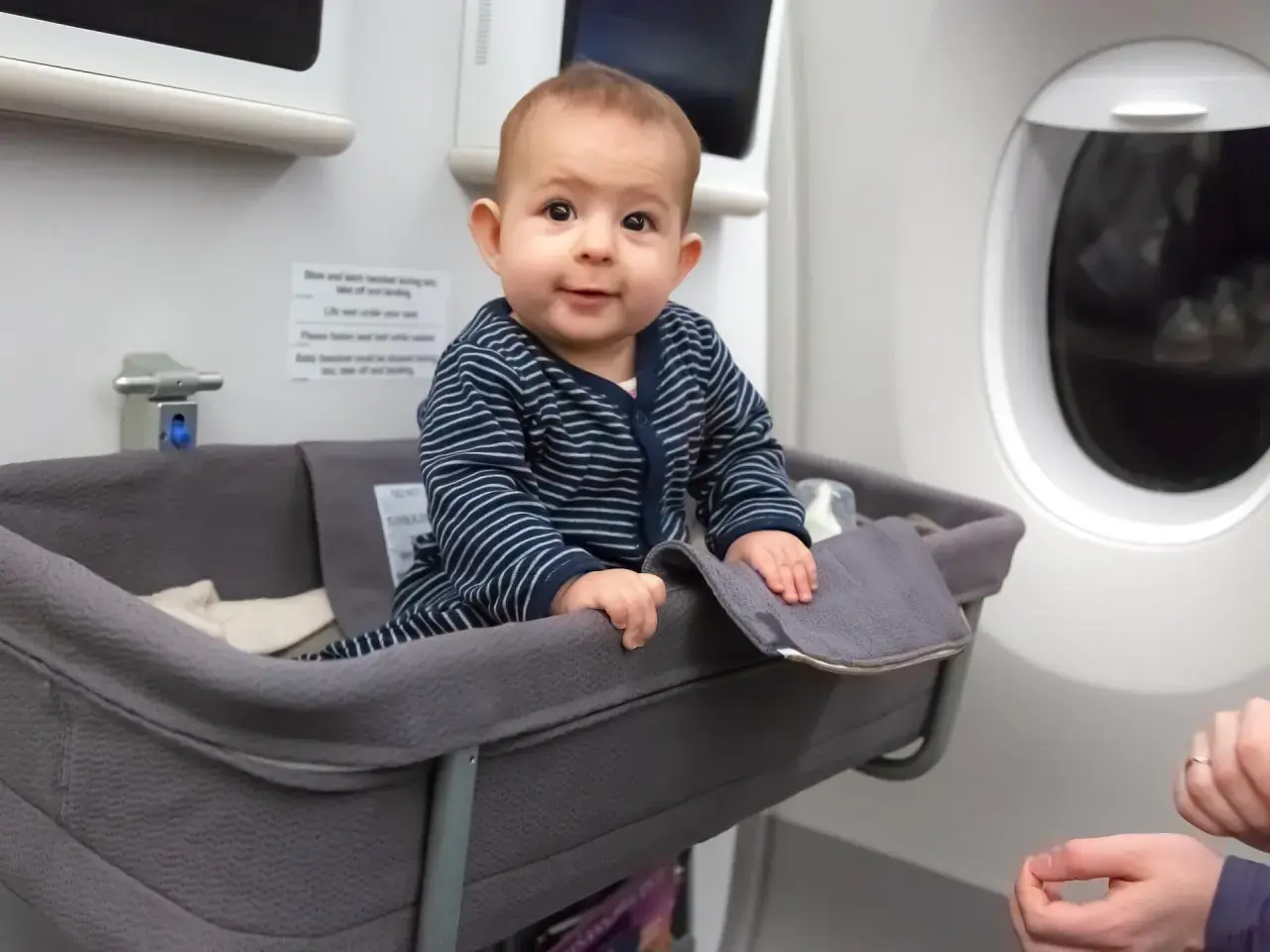 Kleines Baby in Flugzeug-Babywiege, der beste Sitzplatz im Flugzeug mit Kleinkind für eine entspannte Reise.