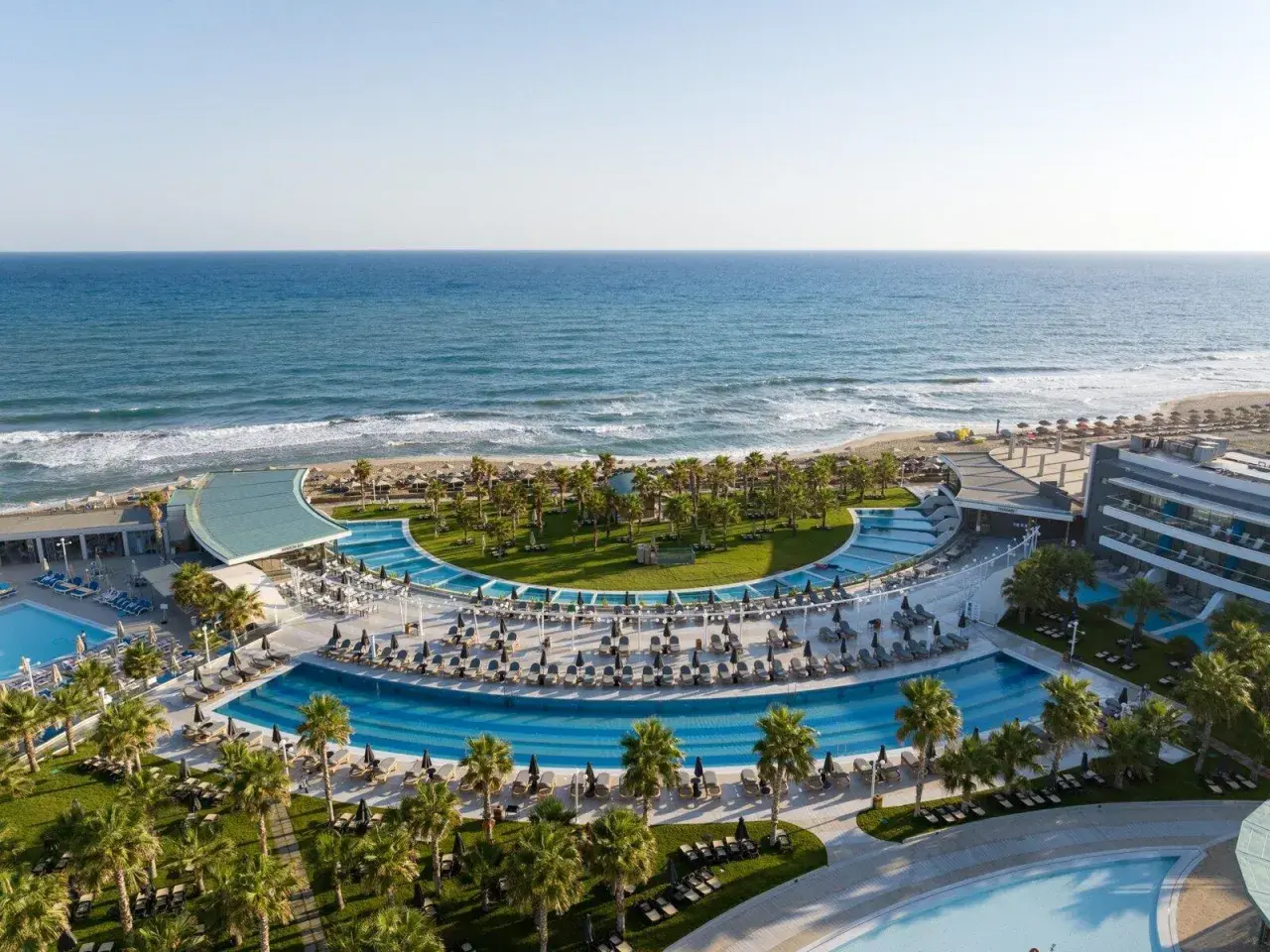 Traumhafter Blick auf das Lyttos Mare auf Kreta: Palmen, Pools und das azurblaue Meer.