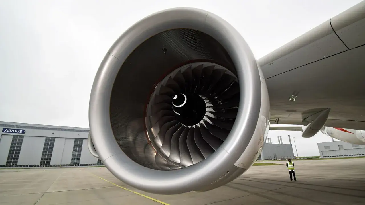 Detailaufnahme eines riesigen Triebwerks der A380. Im Hintergrund die Airbus-Halle und eine Person in Warnweste.