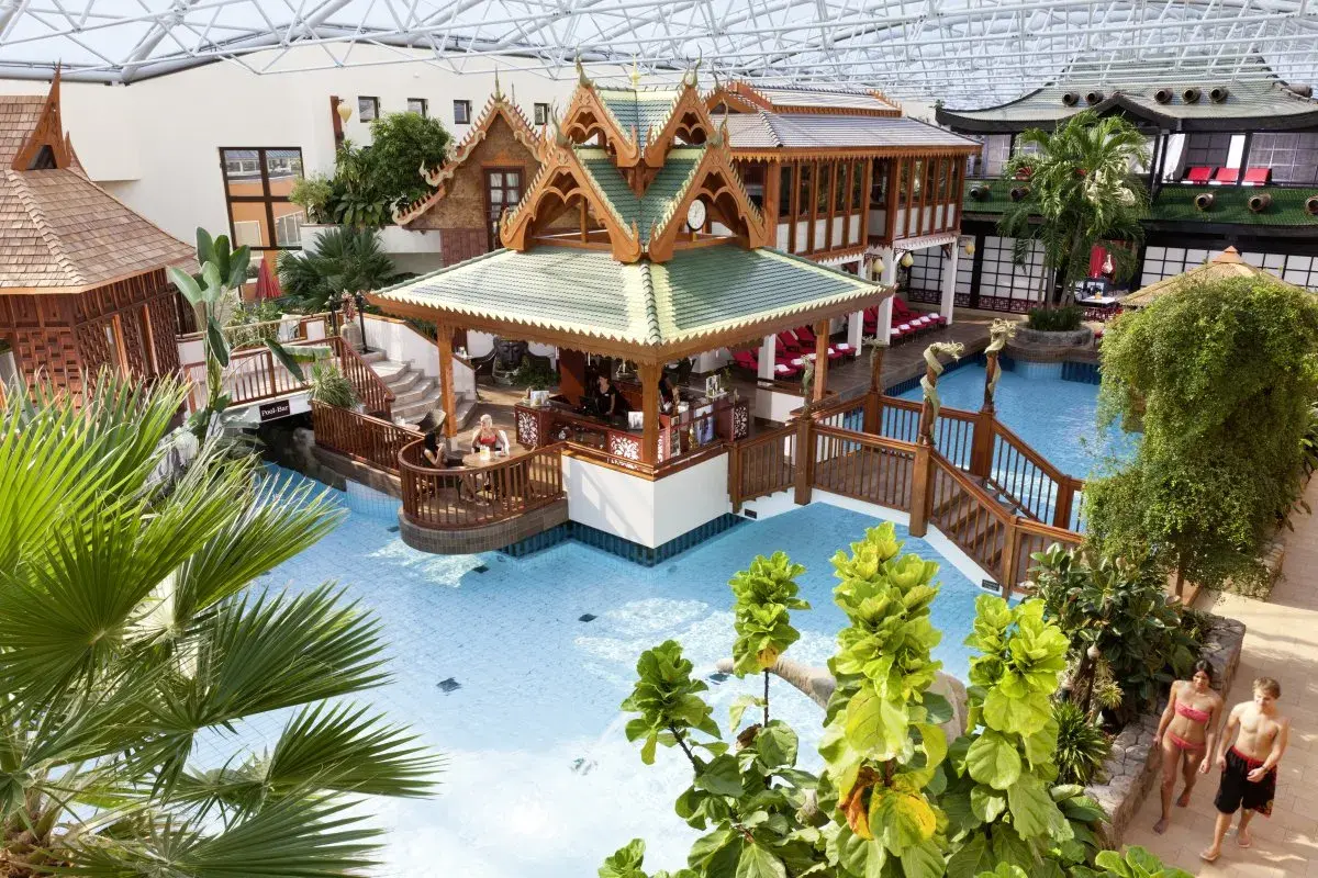 Tropisches Paradies im Sieben Welten Hotel & Spa Resort: Poollandschaft mit asiatischem Flair, Bar und Palmen.