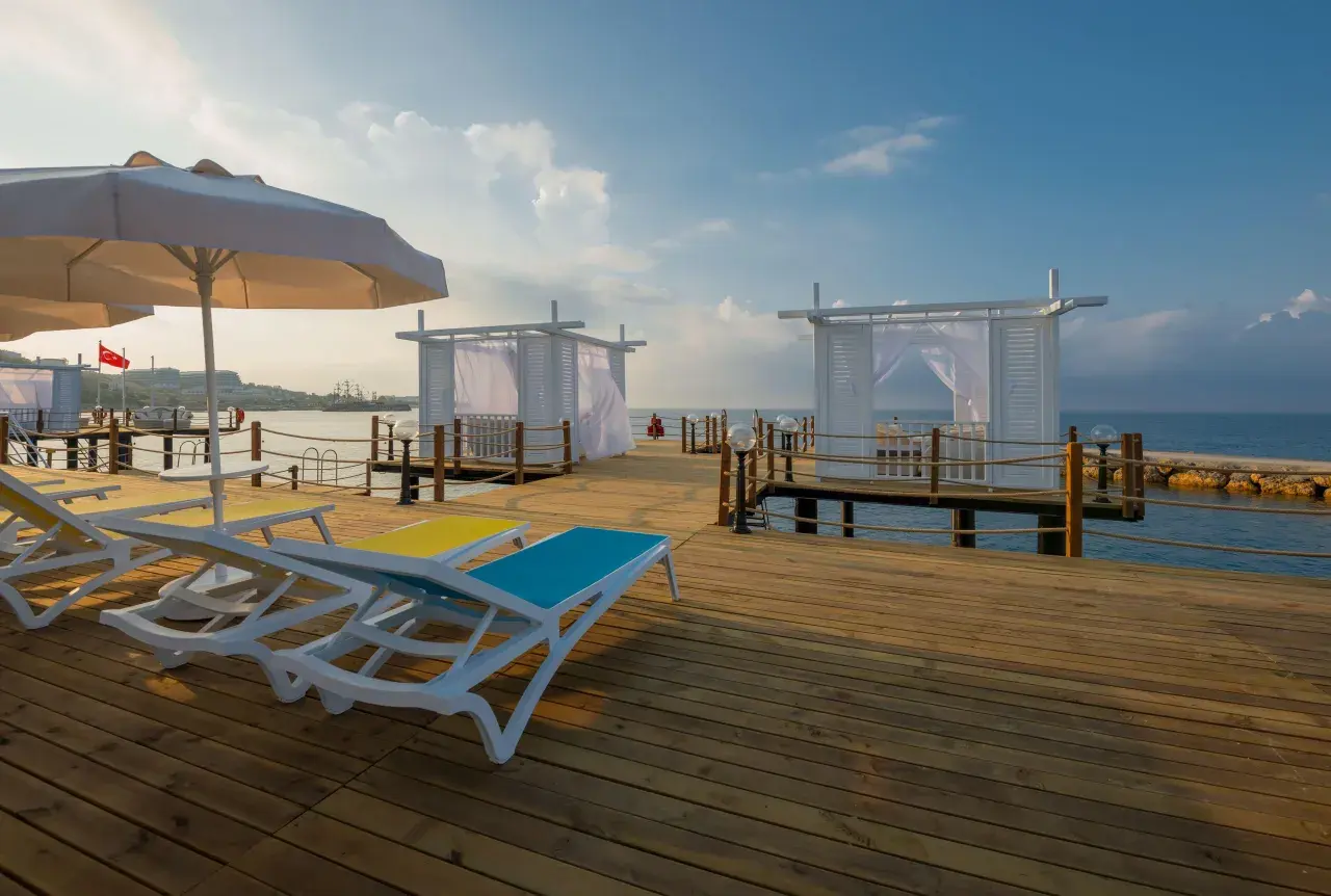 Sonnenliegen und weiße Pavillons auf einem Holzsteg am Meer, ein perfekter Ort für einen Urlaub im Mary Hotel Alanya.