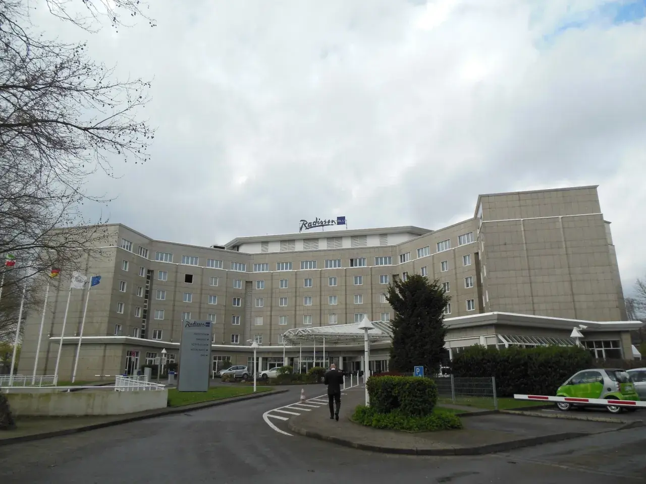 Das Radisson Blu Hotel Dortmund, ein imposantes Gebäude mit vielen Fenstern, empfängt seine Gäste unter einem grauen Himmel.