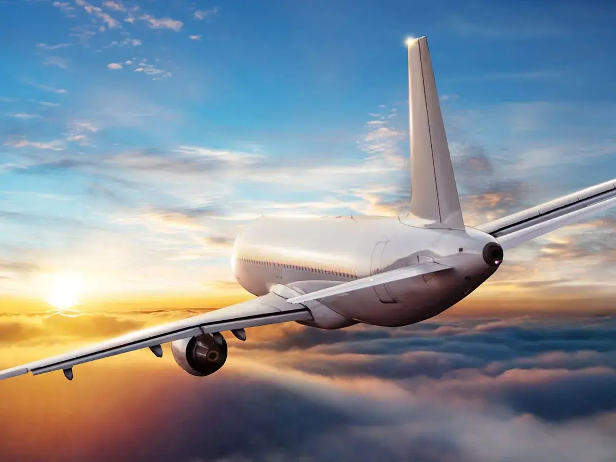 Ein Flugzeug fliegt über Wolken bei Sonnenuntergang. Die Frage, wie sicher ist fliegen aktuell, wird durch diese friedliche Szene beantwortet.