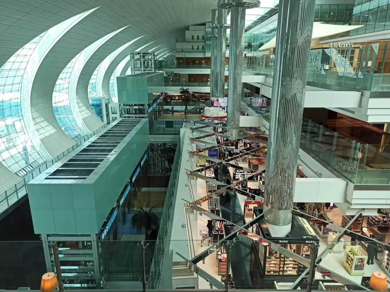 Der Flughafen Dubai innen: ein modernes Einkaufsparadies mit Glas und Stahl. Helle Gänge, Geschäfte und Palmen laden zum Verweilen ein.