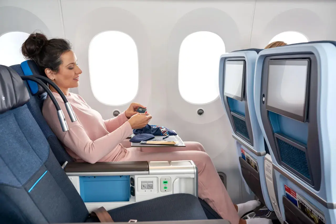 Frau im KLM Flugzeug entspannt sich mit einem kleinen Beutel.