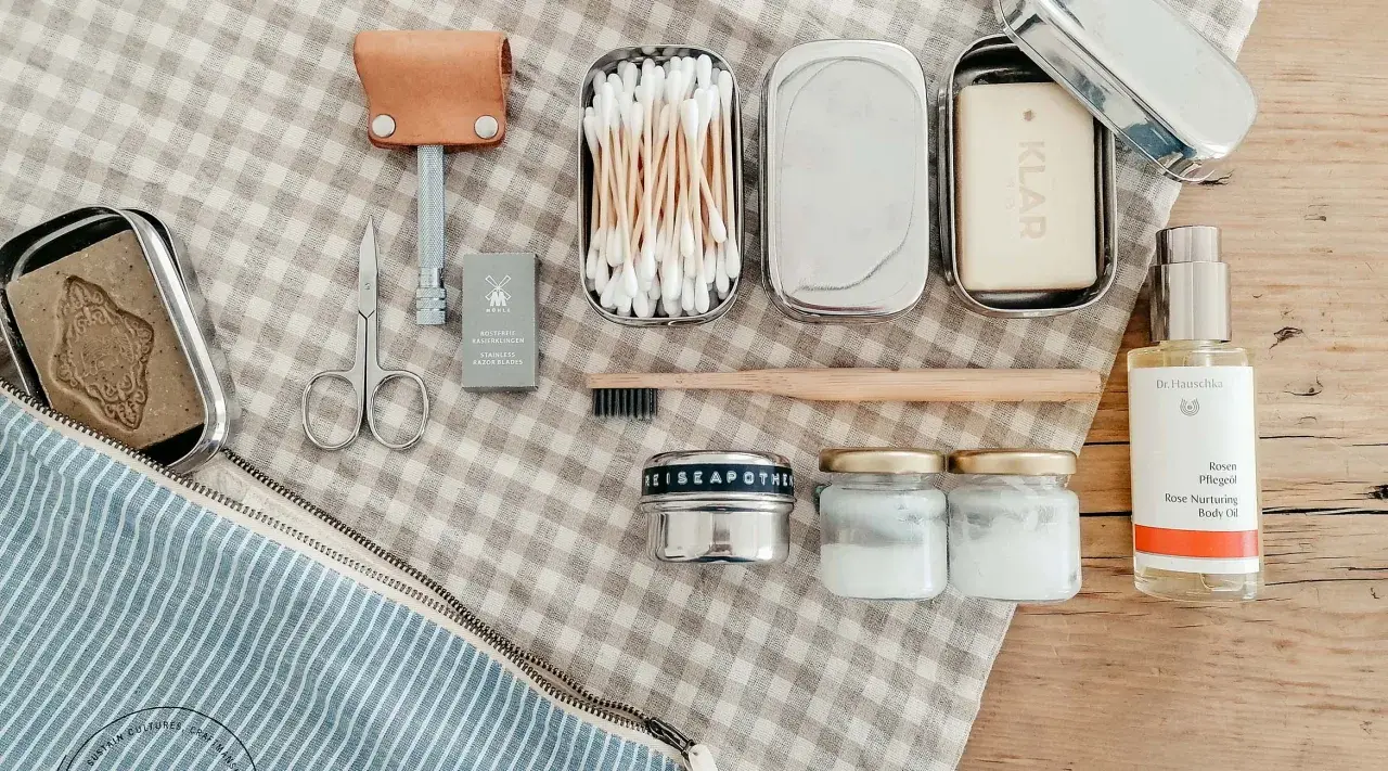 Kosmetik urlaub liste: Rasierer, Seife, Wattestäbchen, Zahnbürste, Cremetiegel und Rosenöl für die Reiseapotheke.