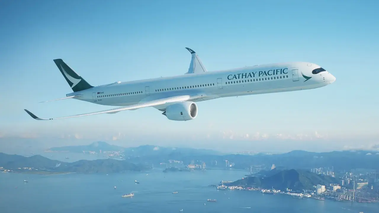 Cathay Pacific Sicherheit: Ein modernes Flugzeug fliegt über einer Stadt und dem Meer.