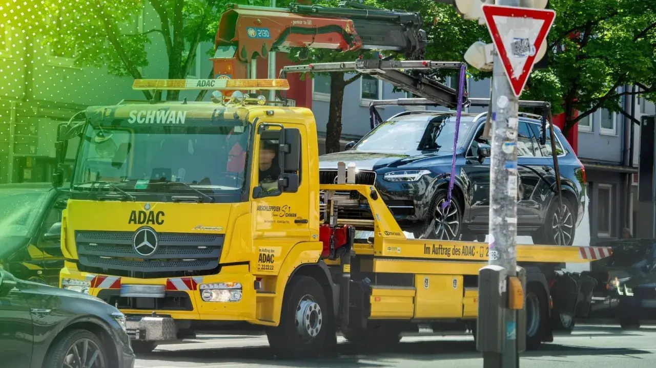 Gelber ADAC Abschleppwagen mit dunklem SUV auf der Ladefläche in Berlin. Informiert über die Kosten für Abschleppen in Berlin.