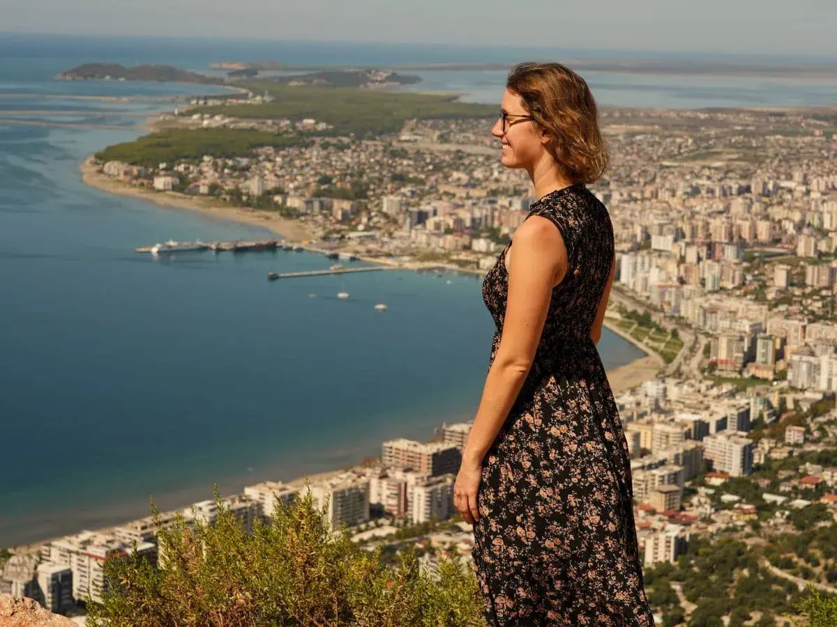 Frau genießt den Ausblick auf eine Stadt am Meer während ihres Urlaubs in Albanien.