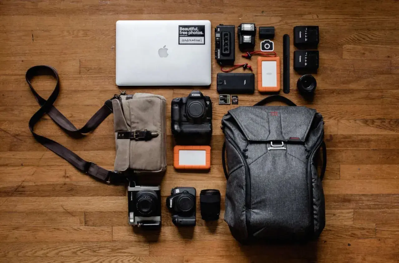 Perfekte work and travel packliste: Laptop, Kameras, Objektive, Speicherkarten, externe Festplatten, Blitzgeräte und ein Rucksack.