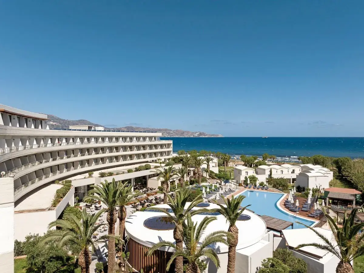 Agapi Beach Resort mit geschwungener Architektur, Pool und Palmen am Meer.