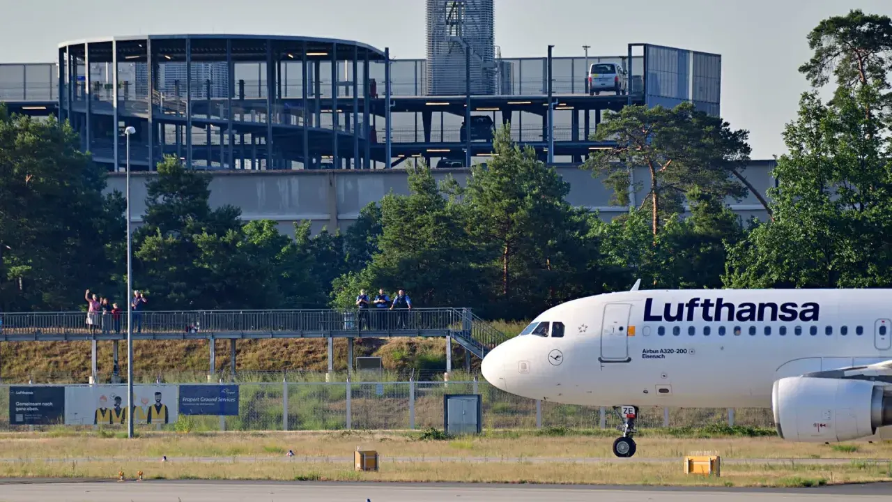 Lufthansa Airbus A320-200 auf dem Rollfeld in Frankfurt. Im Hintergrund ein Parkhaus und Bäume.