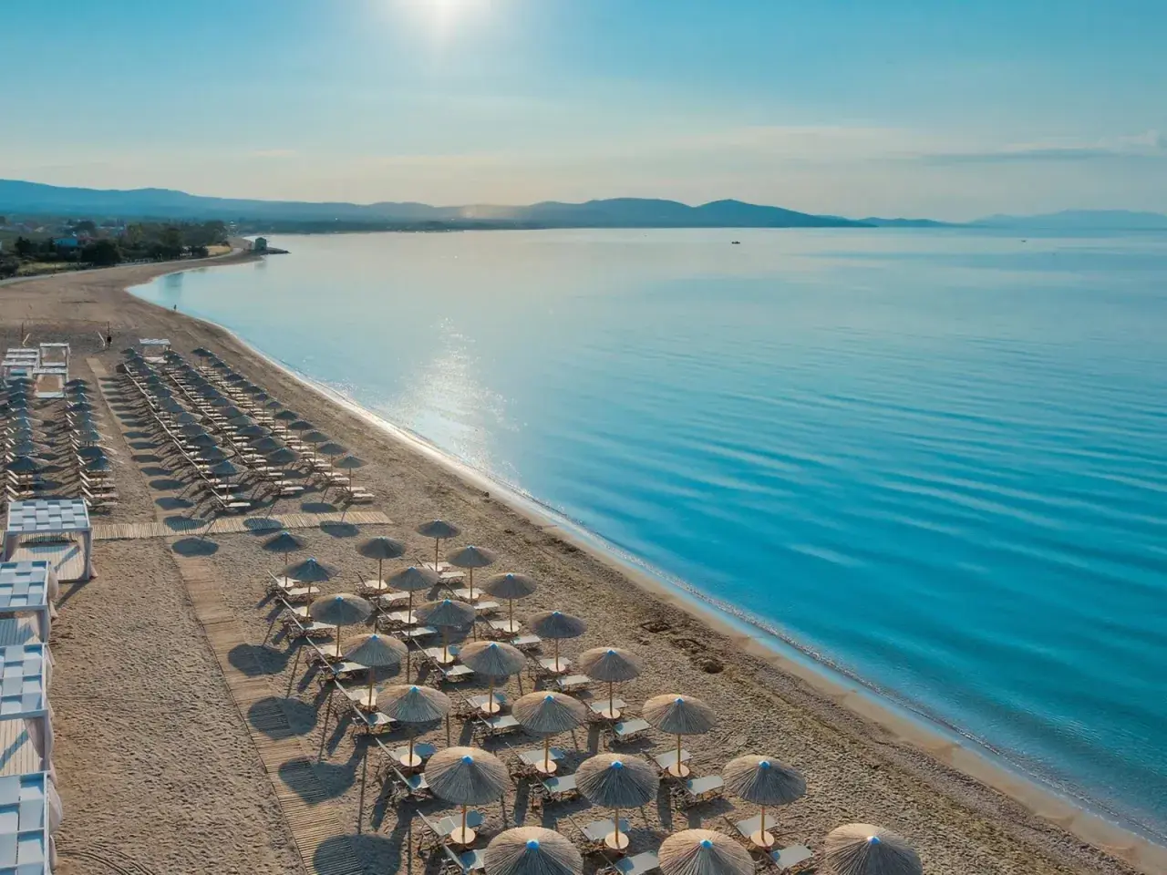 Ein traumhafter Strand mit vielen Liegen und Sonnenschirmen, bereit für Gäste des TUI Blue Lagoon Princess. Das Meer glitzert in der Sonne.