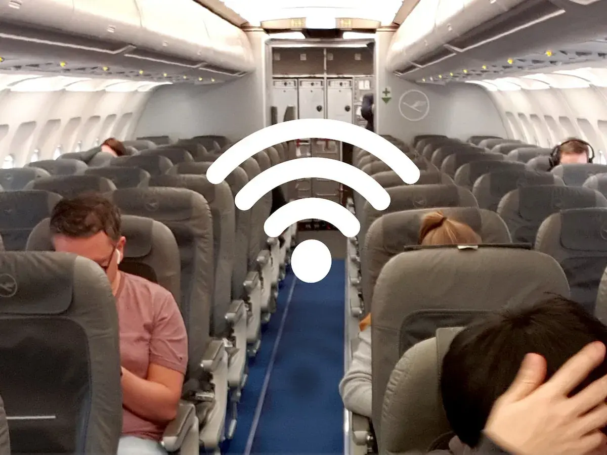 WLAN im Flugzeug: Passagiere sitzen in Reihen auf Flugzeugsitzen, während ein großes WLAN-Symbol über ihnen schwebt.