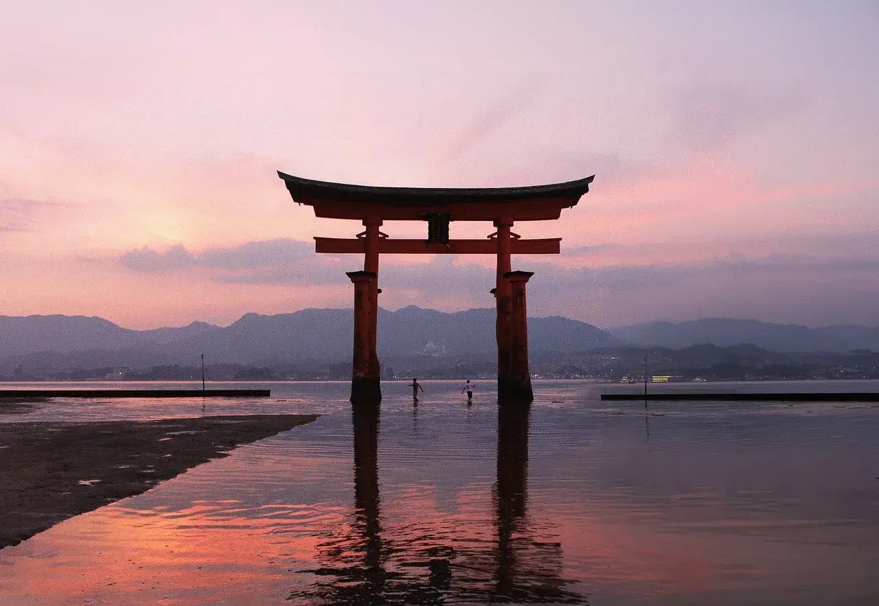 Ein rotes Torii-Tor im Wasser bei Sonnenuntergang. Ein unvergesslicher Moment auf einem Japan Urlaub.