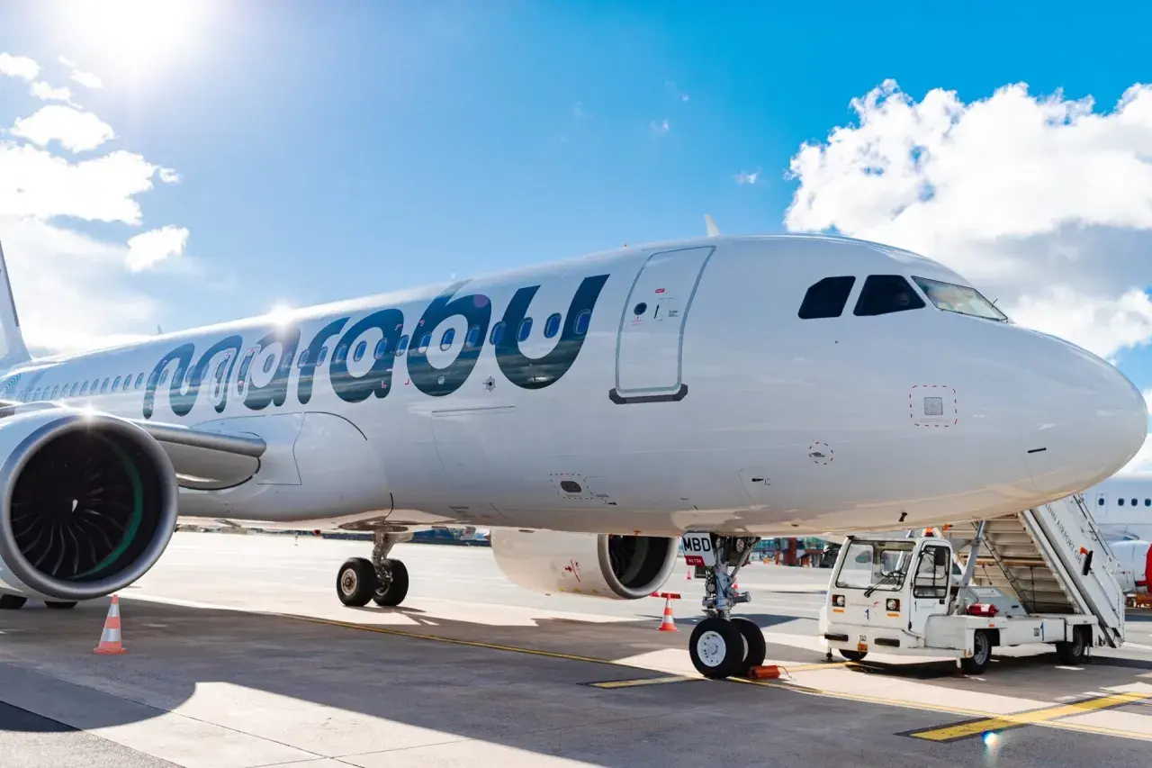 Ein weißes Flugzeug der Marabu Airlines steht am Flughafen. Die Sonne scheint auf den Rumpf, und eine Treppe ist am Eingang angebracht.
