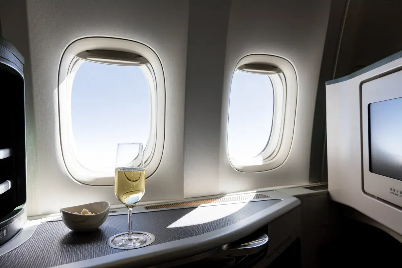 Sektglas und Snack am Fenster im Flugzeug. Ein kostenloses Upgrade Flug, das den Luxus genießt.