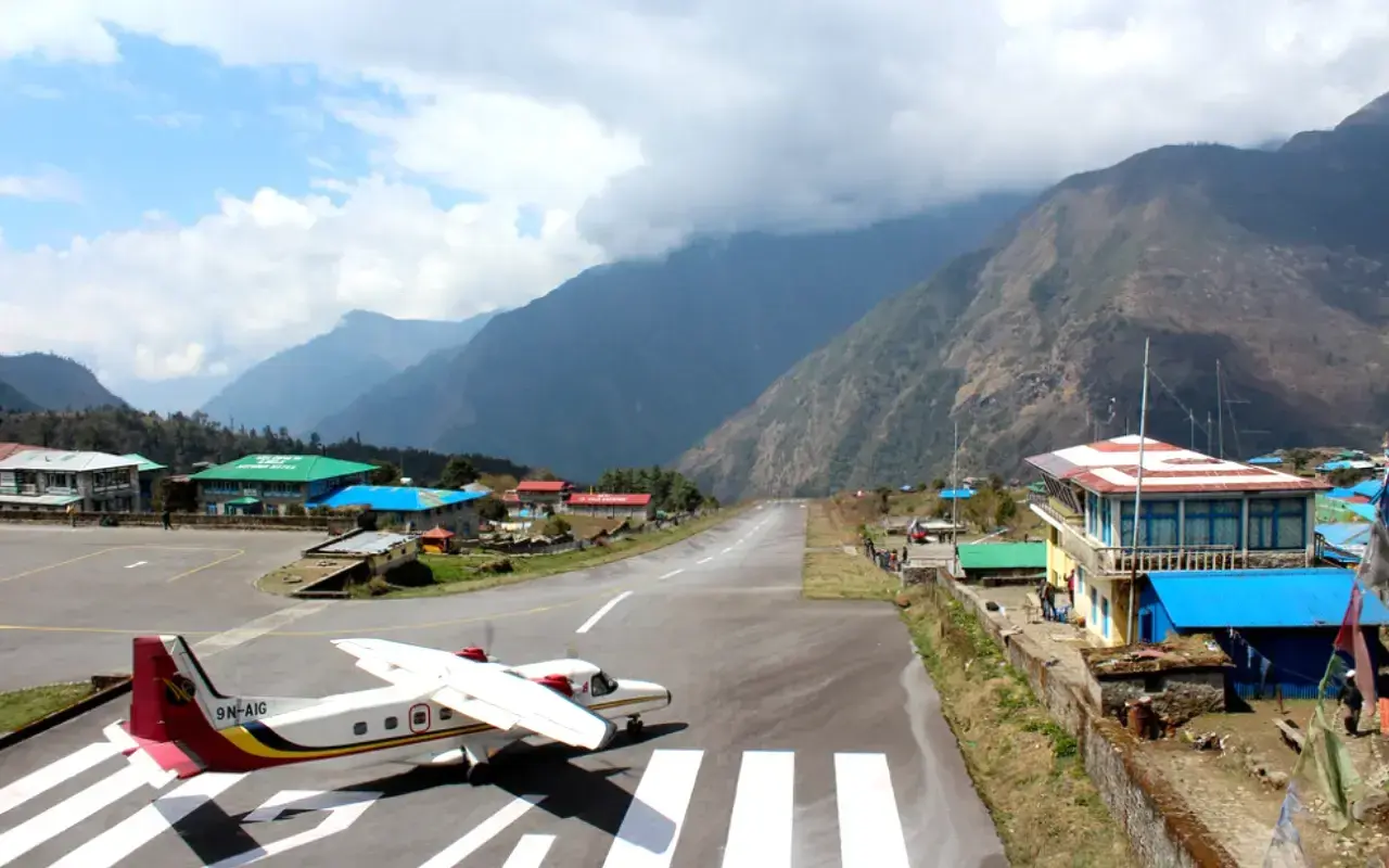 Ein kleines Flugzeug steht auf dem Rollfeld des Nepal Flughafens, umgeben von majestätischen Bergen.