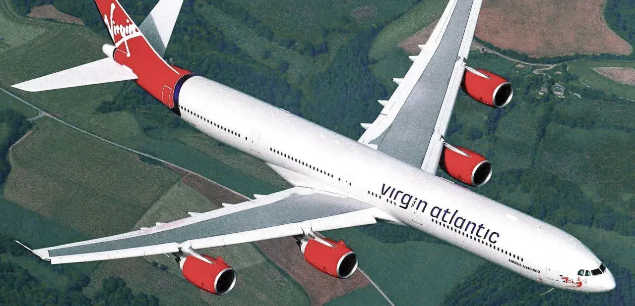 Ein Airbus A340-600 der Virgin Atlantic Flotte fliegt über grüne Landschaften.