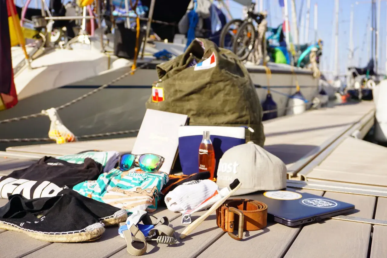 Packliste Segeln: Kleidung, Sonnenbrille, Zahnbürste, Gürtel, Laptop und eine Tasche. Bereit für das Abenteuer auf dem Wasser!