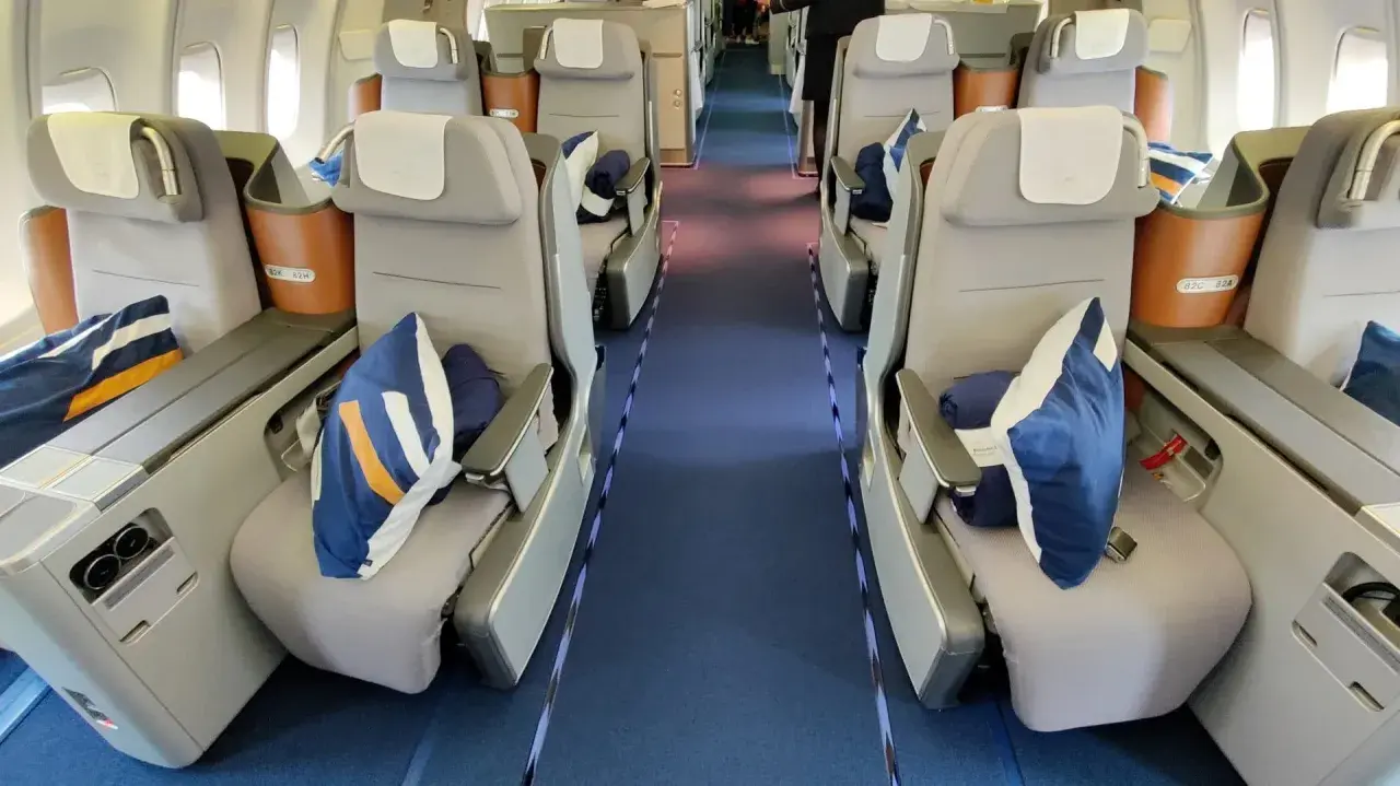 Lufthansa Business Class Sitze mit blauen Kissen und Decken. Ein Blick in den Gang, der Hoffnung auf einen Standby-Ticket-Lufthansa-Traumflug macht.