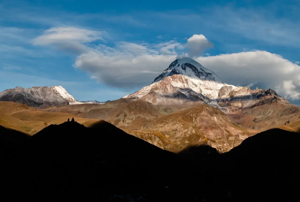 Majestätische Berge in Georgien, ein unvergesslicher Urlaub. Die Gergeti-Dreifaltigkeitskirche thront auf einem Hügel vor dem schneebedeckten Gipfel des Kasbek.