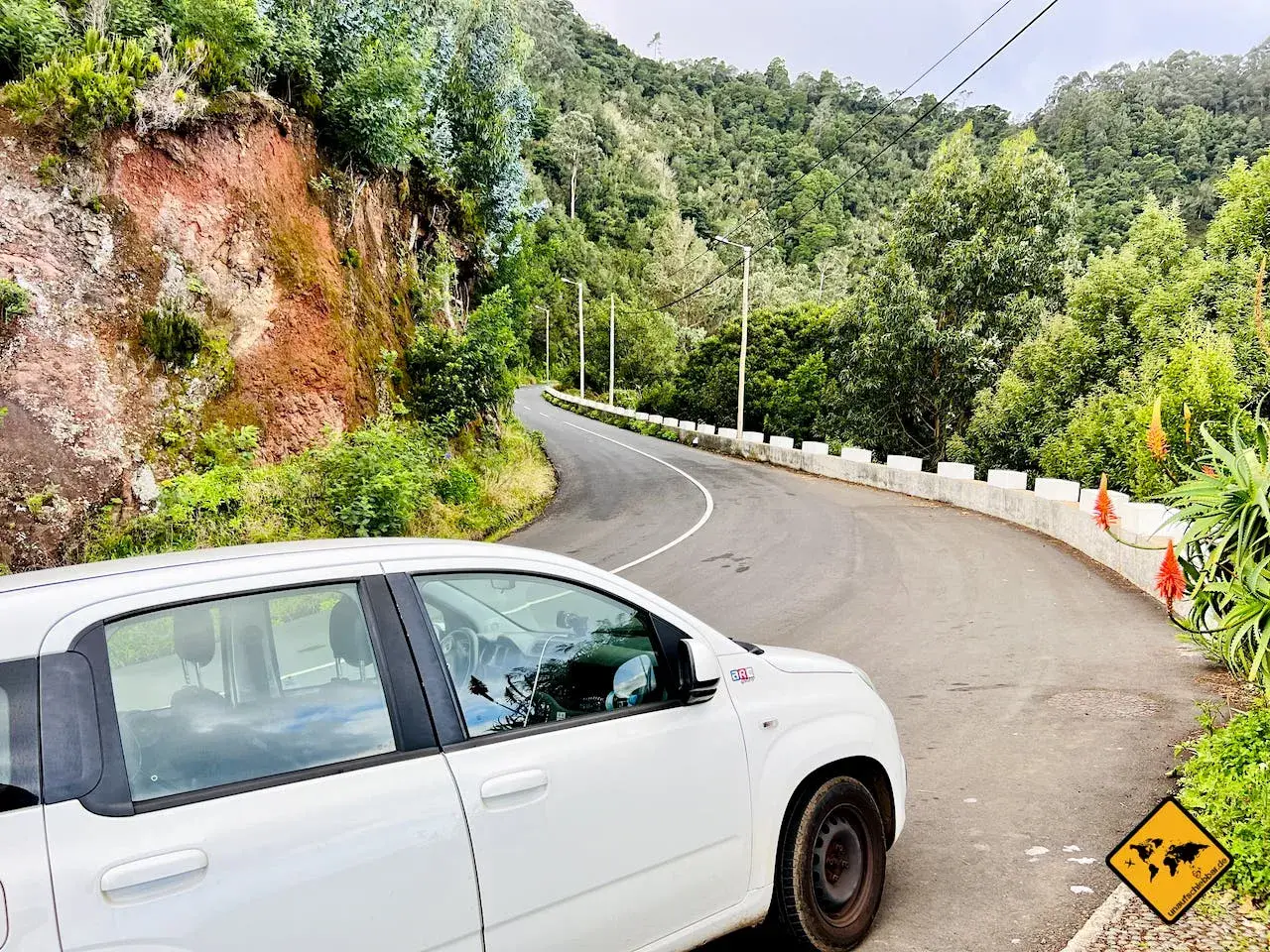 Ein weißer Mietwagen auf einer kurvigen Straße auf Madeira. Braucht man auf Madeira einen Mietwagen? Ja, um diese Aussicht zu genießen!