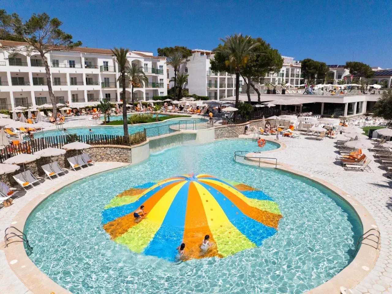 Bunte Wasserrutsche im Pool des Viva Cala Mesquida Resort & Spa. Kinder planschen im Wasser.