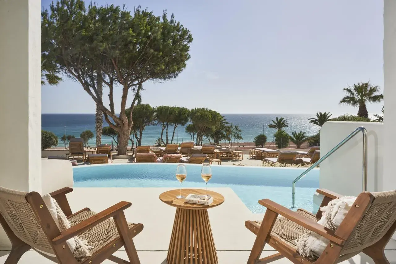 Entspannter Blick vom daia slow beach hotel conil auf den Pool und das Meer. Zwei Gläser Wein und ein Buch warten auf Sie.