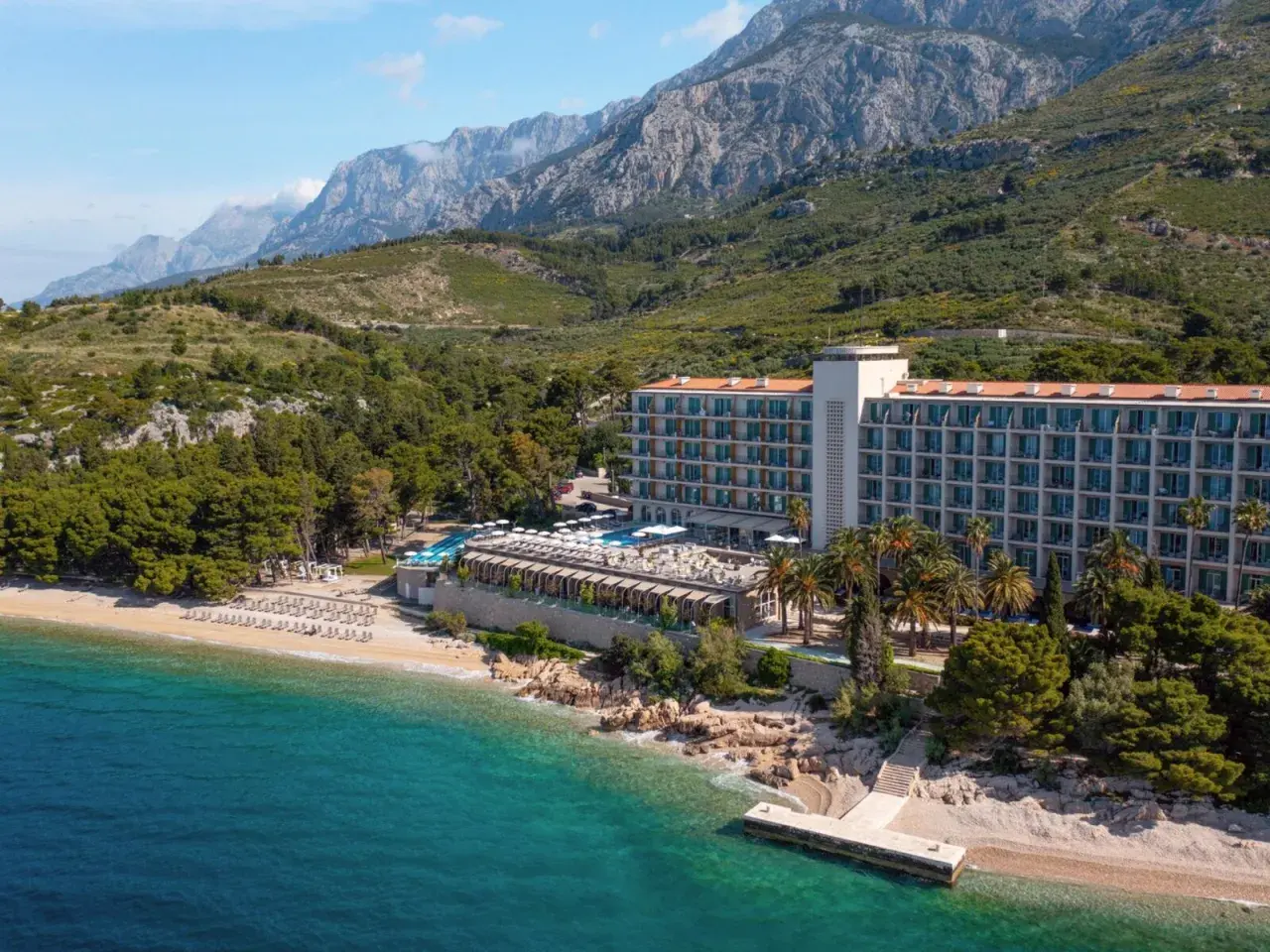 TUI Blue Jadran: Ein Hotel am Strand mit Pool und Bergen im Hintergrund, an der türkisfarbenen Adria.
